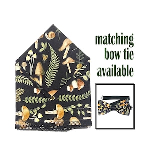 Puede incluir: Un pañuelo de bolsillo negro con un patrón de setas y helechos. El texto "corbata de lazo a juego disponible" está impreso en un rectángulo blanco en la esquina superior derecha de la imagen.