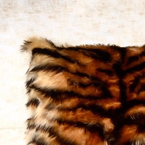 Puede incluir: Un coj&iacute;n de sof&aacute; de piel sint&eacute;tica marr&oacute;n y negro con un patr&oacute;n de rayas de tigre.