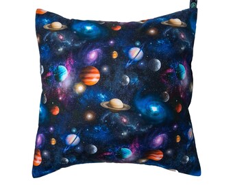 May include: A square pillow with a dark blue background featuring a repeating pattern of planets and stars. The planets are in shades of orange, red, blue, and green.