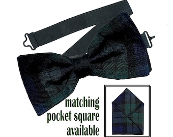 May include: A black bow tie with a green and blue plaid pattern. The bow tie is attached to a black elastic band. The image also shows a matching pocket square with the same plaid pattern. "Matching pocket square available" is written below the image.