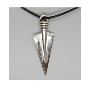 May include: Silver arrowhead pendant necklace with a black cord. The arrowhead is a simple design with a pointed tip and a flat base.