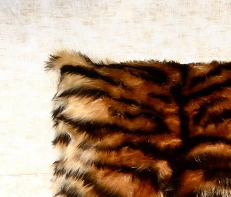 Puede incluir: Un coj&iacute;n de sof&aacute; de piel sint&eacute;tica marr&oacute;n y negro con un patr&oacute;n de rayas de tigre.