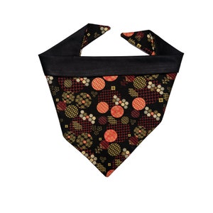 May include: Black bandana with a geometric pattern of red, gold, and white circles on a black background. The bandana has a black border.