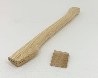 May include: A wooden axe handle with a wedge for attaching the axe head. The handle is made of light-coloured wood with a natural grain pattern.