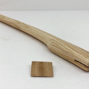 Könnte beinhalten: Ein Holz-Axt-Stiel mit natürlicher Oberfläche. Der Stiel ist am Ende gespalten, mit einem kleinen Holzkeil, der zum Befestigen des Kopfes eingesetzt wird.