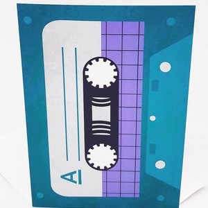 May include: A teal blue card with a silver cassette tape design. The cassette tape has a purple grid pattern and the word "A1" printed on it.