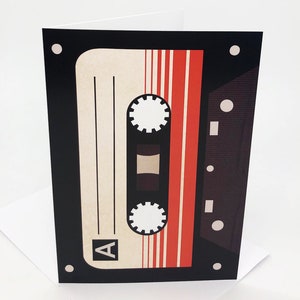 May include: A black and red cassette tape with the letter "A" on the side. The tape is on a white background.