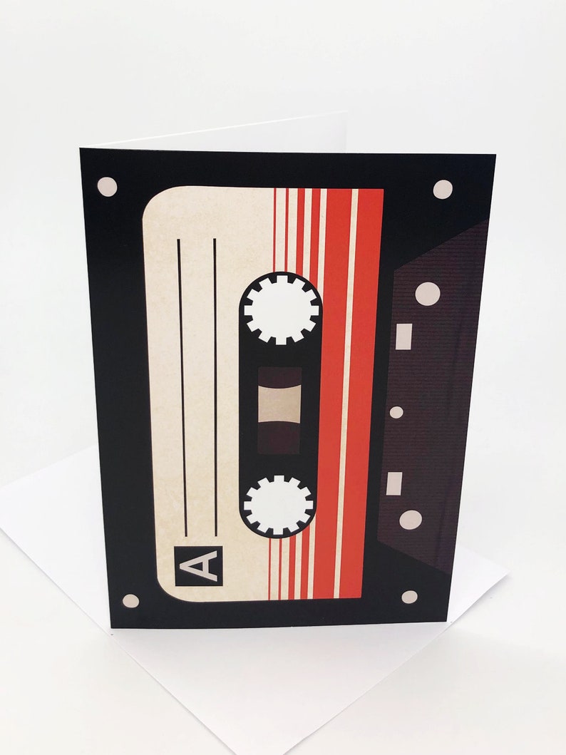 May include: A black and red cassette tape with the letter "A" on the side. The tape is on a white background.