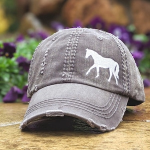 May include: A white ceramic mug with a black handle and the text "But First, Coffee" in a black, handwritten-style font. The mug is on a white surface.