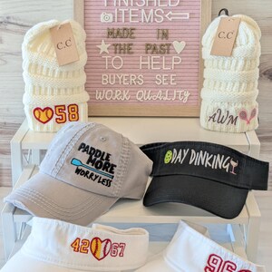a collection of hats and caps with various embroidered designs, including numbers and text, arranged on a shelf.