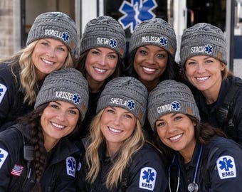 May include: A group of seven gray cable-knit beanies, each featuring a brown leather-style patch with a blue and white Star of Life emblem and a custom embroidered name. The names include Donell, Beth, Melissa, Stacy, Krisie, Sheila, and Ginny.