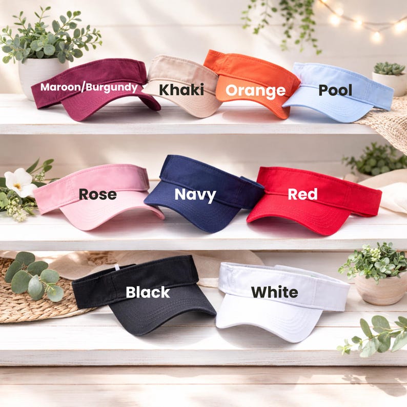 A collection of colorful visor hats is displayed on a shelf, each with a different color and labeled with the corresponding color name.