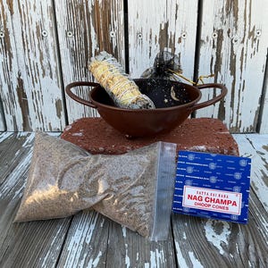 May include: An assortment of spiritual items, including a bundle of sage, a small brown bowl, a package of incense cones, and two bags of loose incense. The sage bundle is wrapped with twine. The incense cones are in a blue box with white text.