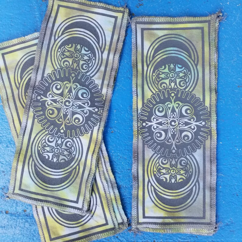 Op de afbeelding: Twee stoffen patches met een groene, gele en witte tie-dye achtergrond. De patches hebben een zwart-wit mandala-ontwerp met een cirkelvormig patroon.