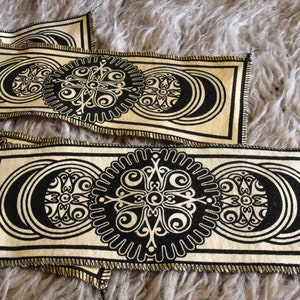 May include: A set of four beige fabric patches with black and white intricate designs. The designs feature a repeating pattern of circles and swirls.