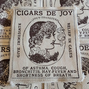 May include: A beige fabric patch with the text "CIGARS DE JOY" and an illustration of a person smoking. The patch also includes text about relief for asthma, cough, bronchitis, hay fever, and shortness of breath.