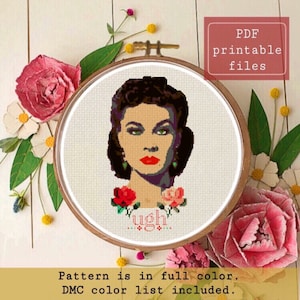 Può includere: Uno schema di ricamo a punto croce che presenta una donna con capelli scuri e labbra rosse, che indossa una collana verde e circondata da rose rosse. Il testo "ugh" è ricamato sotto il viso della donna. Lo schema è a colori e include un elenco di colori DMC.