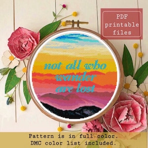 Può includere: Un modello a punto croce in un telaio di legno, con un design colorato del tramonto con il testo "not all who wander are lost". L'immagine include fiori rosa e bianchi e il testo "PDF printable files."