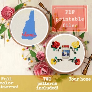 Può includere: Due schemi di punto croce, uno con lo stato del New Hampshire con la parola "home" e l'altro con un barattolo di fluff di marshmallow con rose. Entrambi gli schemi sono in cerchi da ricamo e circondati da fiori.