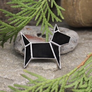 Pode incluir: Broche de vidro preto em forma de c&atilde;o com um design geom&eacute;trico. A broche &eacute; feita de vidro preto e metal prateado.