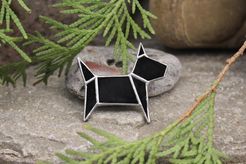Pode incluir: Broche de vidro preto em forma de c&atilde;o com um design geom&eacute;trico. A broche &eacute; feita de vidro preto e metal prateado.