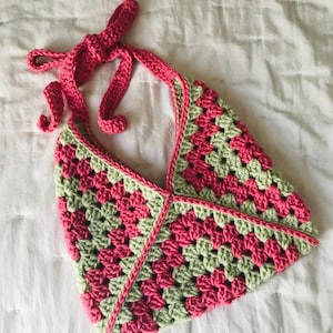 May include: A crocheted halter top with a pink and green granny square pattern. The top has a long tie that can be tied at the neck.