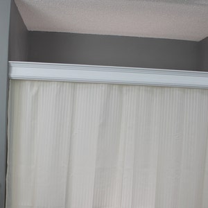 May include: A bathroom scene featuring a white shower curtain with vertical stripes, framed by a white decorative molding. The walls are painted gray, and a sign that says "All you need is love and a dog" is visible.