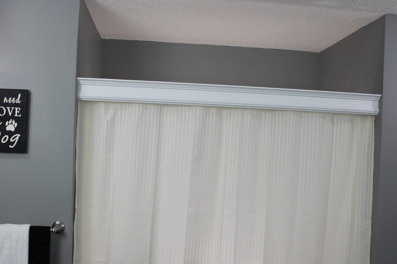 May include: A bathroom scene featuring a white shower curtain with vertical stripes, framed by a white decorative molding. The walls are painted gray, and a sign that says "All you need is love and a dog" is visible.