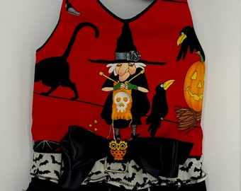 May include: A red pet harness featuring a Halloween print of a witch knitting, black cats, crows, and a jack-o'-lantern. The harness includes a black satin bow with an owl charm, a metal D-ring, and a bottom trim of white bat-print fabric and black tulle.