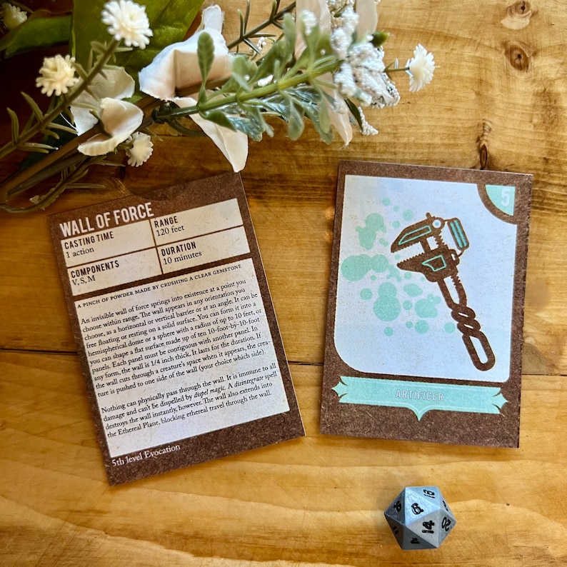 May include: A brown card with the text "Wall of Force" and a description of the spell. The card is next to a blue card with a wrench icon and the text "Artificer" and the number "5".