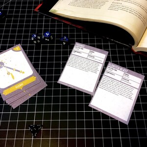 May include: A close-up of a tabletop game with cards featuring the text "Friends", "Eldritch Blast", and "Cleric". The cards are on a black grid surface with blue dice scattered around.