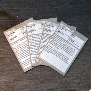 May include: Close-up of five beige cards with text describing different spells. The cards are titled "Commune", "Summon Celestial", "Dispel Evil", and "Hold Monster".