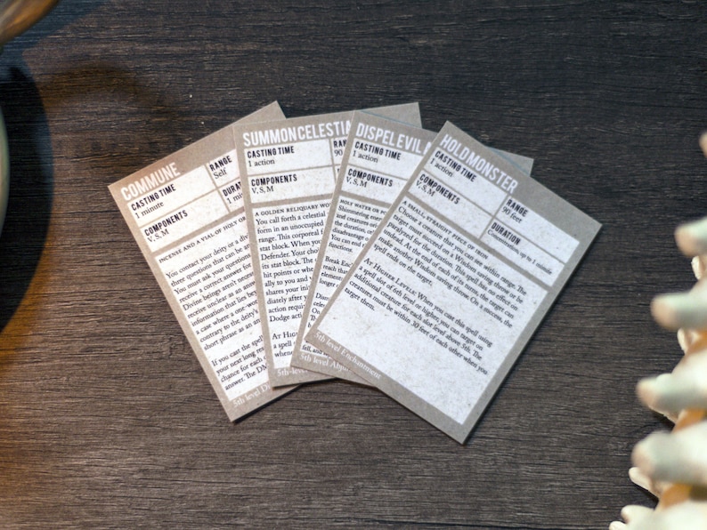 May include: Close-up of five beige cards with text describing different spells. The cards are titled "Commune", "Summon Celestial", "Dispel Evil", and "Hold Monster".