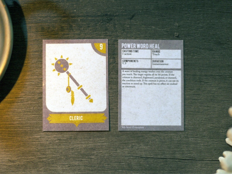 May include: A card game for Dungeons and Dragons featuring a cleric character with a mace and a spell card for Power Word Heal. The card is a light brown colour with black text and a yellow border.
