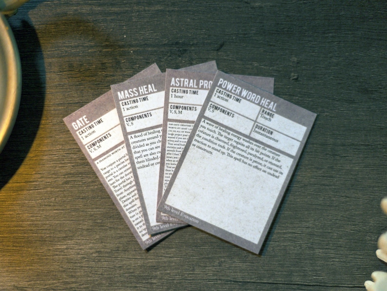 May include: Four cards with text on them, each card has a title, casting time, components, range, and duration. The titles are "Gate", "Mass Heal", "Astral Projection", and "Power Word Heal".