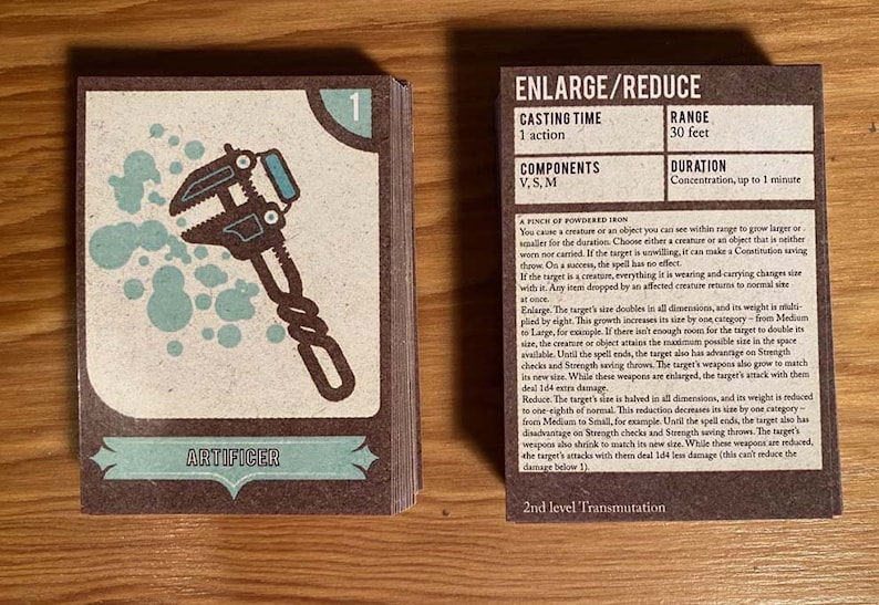 May include: A brown card with a blue and white illustration of a wrench. The card is titled "Artificer" and has the number "1" in the top right corner. The card also has text that reads "Enlarge/Reduce", "Casting Time: 1 action", "Components: V, S, M", "Range: 30 feet", "Duration: Concentration, up to 1 minute", and "A pinch of powdered iron".