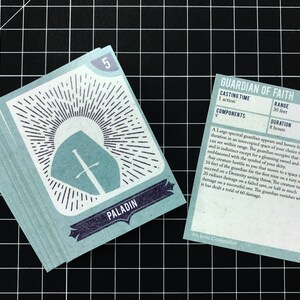 May include: A blue card with a white shield and sword design, labeled "Paladin" and the number "5". A second card, labeled "Guardian of Faith", describes a 4th level Conjuration spell with a range of 30 feet and a duration of 8 hours.