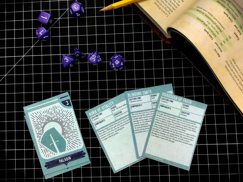 May include: A set of five blue and white dice and four cards with text that reads "Paladin", "Aura of Vitality", "Blinding Smite", and "Guardian of Faith".