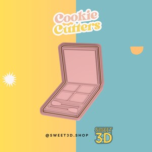 May include: Pink plastic cookie cutter shaped like an open eyeshadow palette with six individual compartments. The cookie cutter is on a yellow and blue background with the text "Cookie Cutters" and "@SWEET3D.SHOP SWEET 3D" in the image.