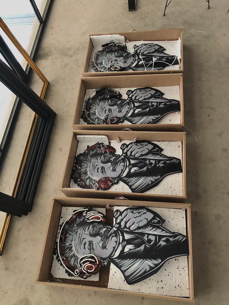 May include: Four framed black and white illustrations of Albert Einstein wearing headphones. The illustrations are in cardboard boxes with white foam padding.