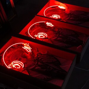 May include: Three framed black and white images of a person with a neon red outline of headphones around their head. The images are displayed in a row, with the top image slightly out of focus.