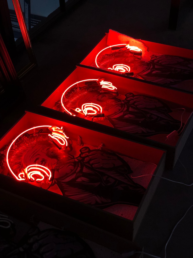 May include: Three framed black and white images of a person with a neon red outline of headphones around their head. The images are displayed in a row, with the top image slightly out of focus.