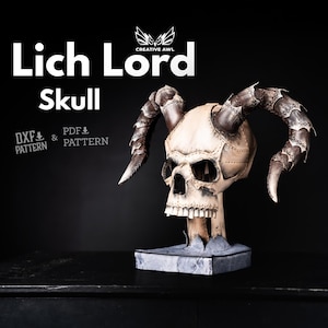 May include: A detailed skull sculpture with large curved horns, set against a black background. The skull is off-white with visible seams and rivets, and the horns are a dark, textured brown. Text on the image reads "Lich Lord Skull" and "DXF & PDF Pattern".