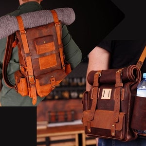 May include: Two leather backpacks with adjustable straps. The larger backpack has a brown and orange color scheme and a roll-top closure. The smaller backpack has a brown and dark brown color scheme and a water bottle holder.
