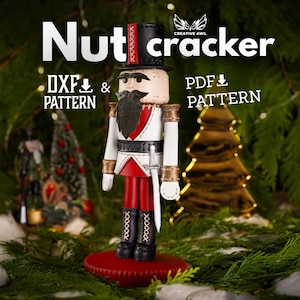 May include: A wooden nutcracker figurine with a red and white uniform, black beard, and a gold sword. The nutcracker is standing on a red base and is surrounded by green foliage.