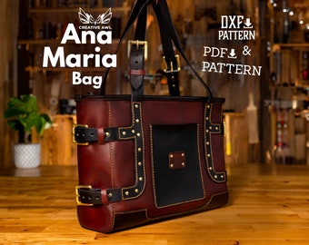 Puede incluir: Un bolso tote de cuero marrón con detalles dorados y correas negras. El bolso tiene un bolsillo frontal y está decorado con tachuelas doradas. El bolso está etiquetado como "Ana Maria Bag" y tiene un logotipo de "Creative Awl".