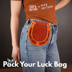 Puede incluir: Un bolso de cuero marrón con forma de herradura que se lleva en un cinturón. El bolso está sujeto a un cinturón de cuero marrón con una hebilla plateada. El bolso tiene una correa de cuero marrón con una hebilla plateada. El bolso lo lleva una persona que lleva pantalones vaqueros azules y una camisa marrón. El texto "Pack Your Luck Bag" es visible en la parte inferior de la imagen.