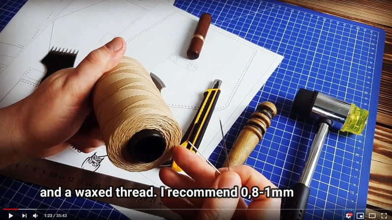 Może przedstawiać: Zbliżenie na szpulkę woskowanej nici, narzędzie do obr&oacute;bki sk&oacute;ry i młotek na niebieskiej macie do cięcia. Tekst "and a waxed thread. I recommend 0,8-1mm" jest widoczny na zdjęciu.