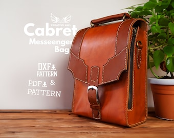 May include: A brown leather messenger bag with a flap closure and a buckle. The bag has a zippered pocket on the side and a white stitch detail. The bag is sitting on a wooden surface with a plant in a terracotta pot in the background. The text "Cabret Messenger Bag" and "DXF & PATTERN" and "PDF & PATTERN" is visible on the white wall behind the bag.