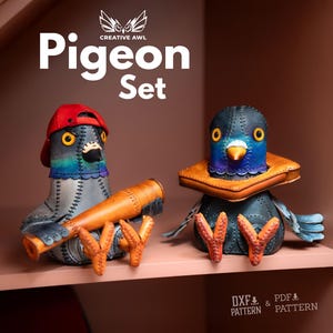 May include: Two handcrafted leather pigeon figurines labeled Pigeon Set by Creative Awl. One pigeon wears a red baseball cap and holds a tan leather telescope. The other pigeon wears a tan leather collar. Both feature stitched details.